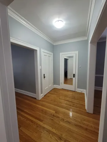 a view of an empty room with wooden floor and closet