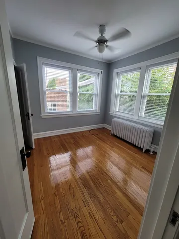 a view of an empty room with a window and hardwood floor