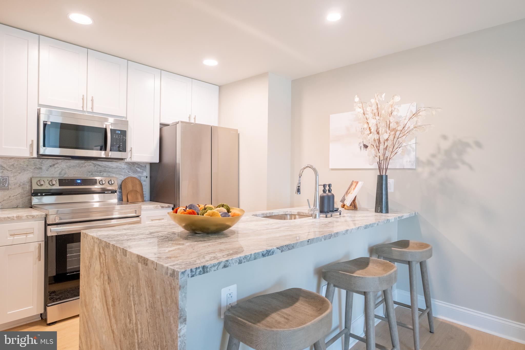 2301-61 John F Kennedy Boulevard, Unit 101 Philadelphia, PA 19103 - Photo 2 of 39 a kitchen with stainless steel appliances granite countertop a sink a stove a refrigerator cabinets and a dining table