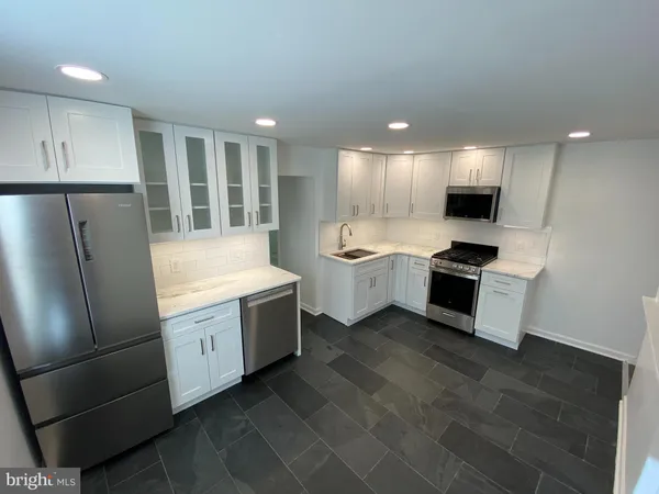 a large kitchen with stainless steel appliances a stove a sink a refrigerator and a cabinets