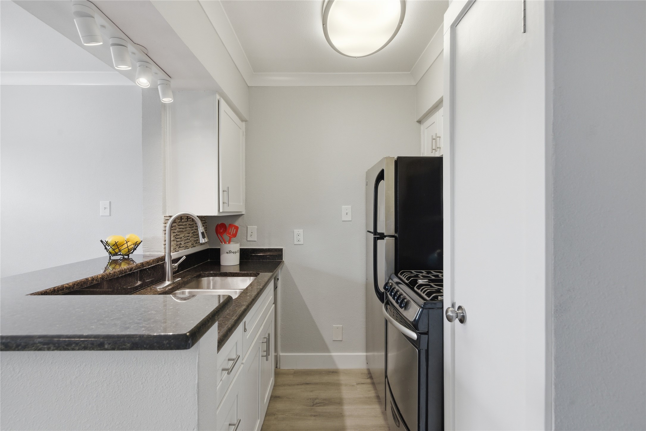 2401 Manor Road, Unit 232 Austin, TX 78722 - Photo 7 of 32 Kitchen with white cabinets, dark granite counters, stainless steel appliances, and ornamental molding