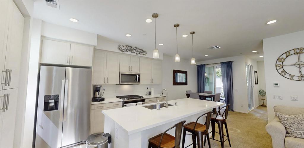 1150 Via Lucero Oceanside, CA 92056 - Photo 4 of 11 a kitchen with kitchen island a appliances dining table and chairs