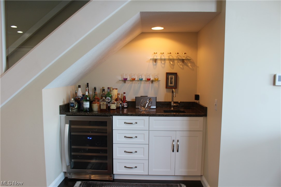 122 Turtle Bay Huron, OH 44839 - Photo 7 of 31 Bar featuring wine cooler, vaulted ceiling, white cabinets, sink, and dark stone countertops