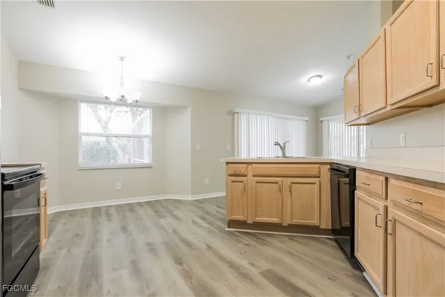 a kitchen with granite countertop a stove a sink and white cabinets with wooden floor