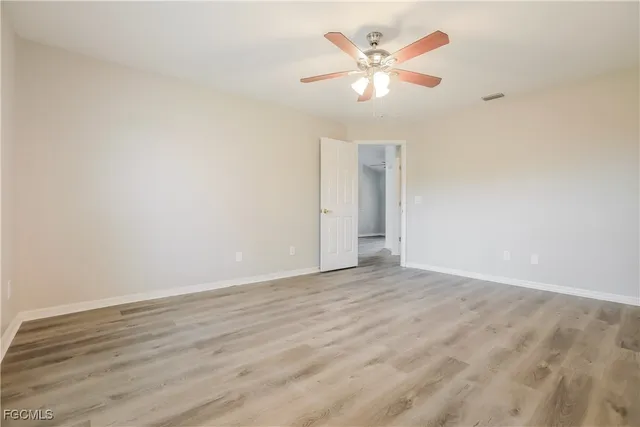 an empty room with wooden floor and ceiling fan