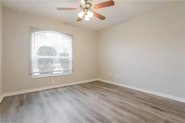 an empty room with a window and a fan
