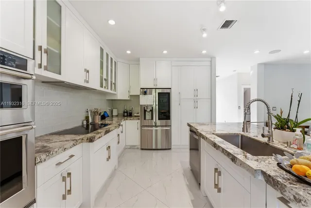 a kitchen with a sink white cabinets and stainless steel appliances