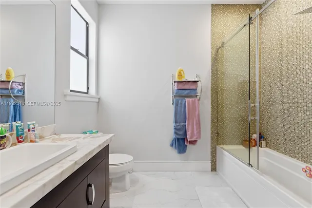 a bathroom with a granite countertop sink a toilet and shower