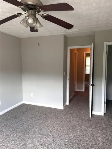 a view of an empty room and chandelier fan