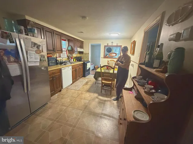 a kitchen with stainless steel appliances granite countertop a refrigerator and chairs
