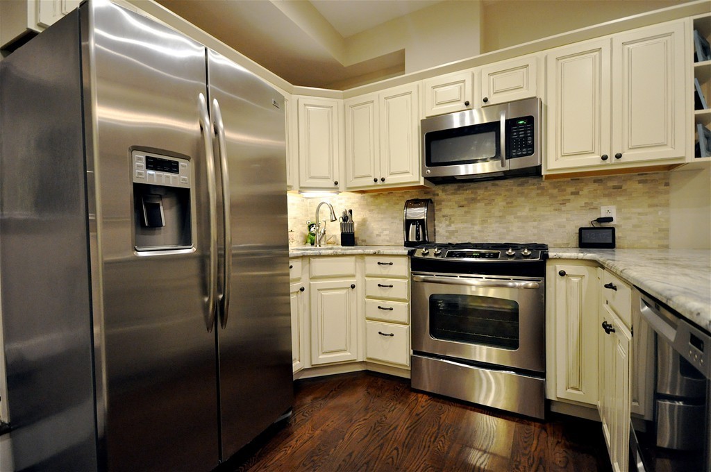 a kitchen with stainless steel appliances and wooden floor