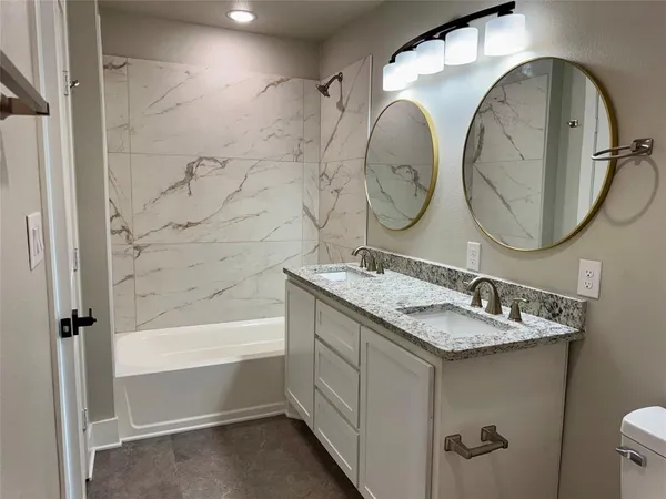 a bathroom with a granite countertop sink mirror toilet and bathtub
