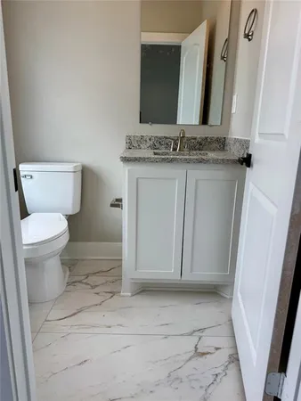 a bathroom with a granite countertop toilet and a sink