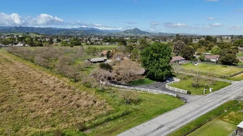 a view of a white house that has a tree in front of it