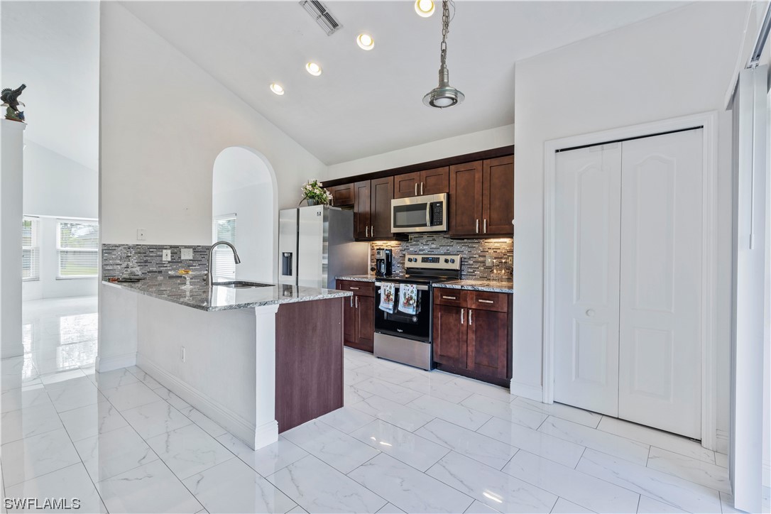 21660 Windham Run Estero, FL 33928 - Photo 15 of 32 a large kitchen with stainless steel appliances a refrigerator and a stove top oven