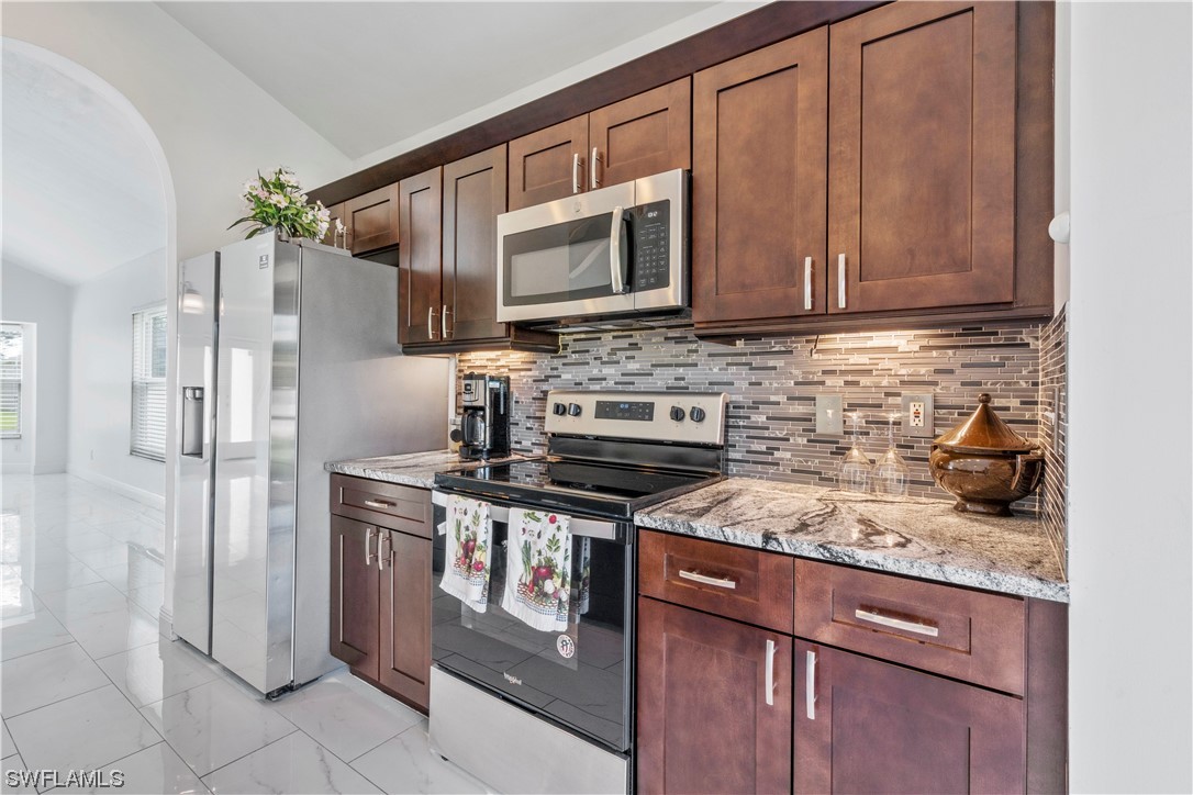 21660 Windham Run Estero, FL 33928 - Photo 17 of 32 a kitchen with stainless steel appliances granite countertop a stove a refrigerator and a microwave