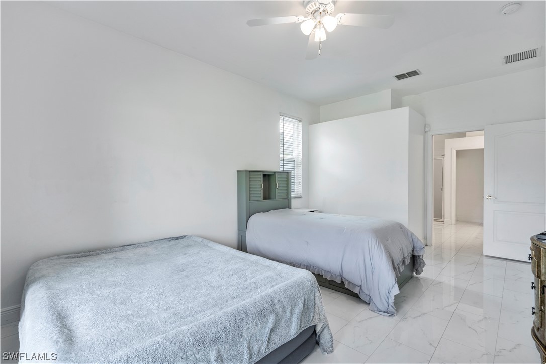 21660 Windham Run Estero, FL 33928 - Photo 20 of 32 a bedroom with two beds and a chandelier