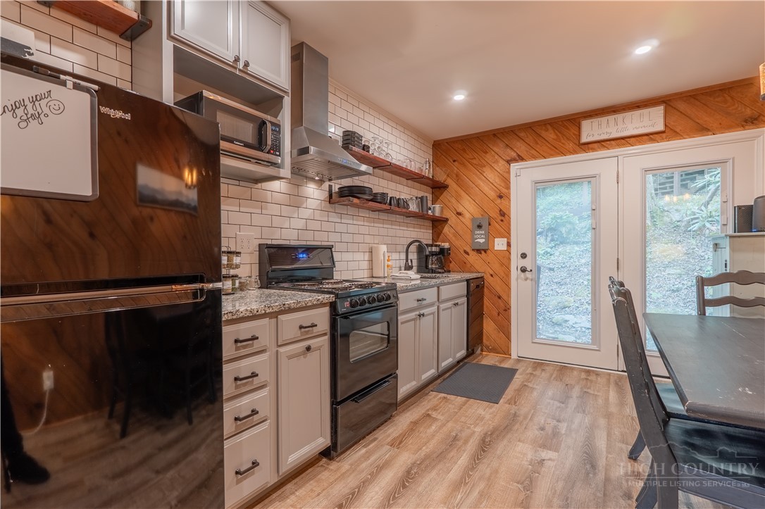 141 Snowflake Road Banner Elk, NC 28604 - Photo 18 of 28 a kitchen with stainless steel appliances a stove a sink dishwasher a refrigerator white cabinets and wooden floor