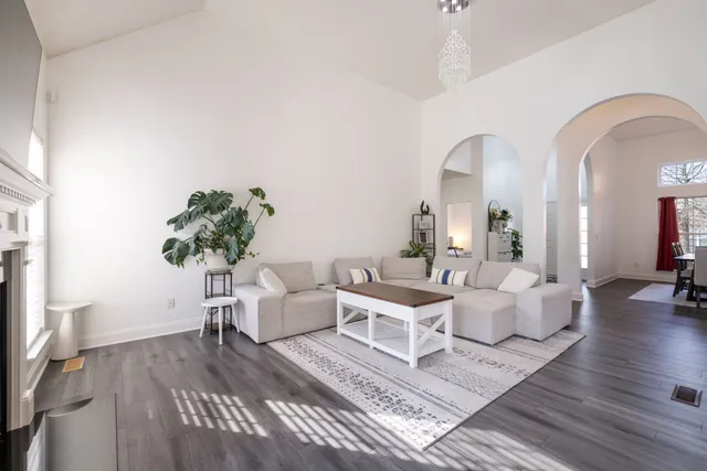 a living room with couches potted plants and a large window with wooden floor