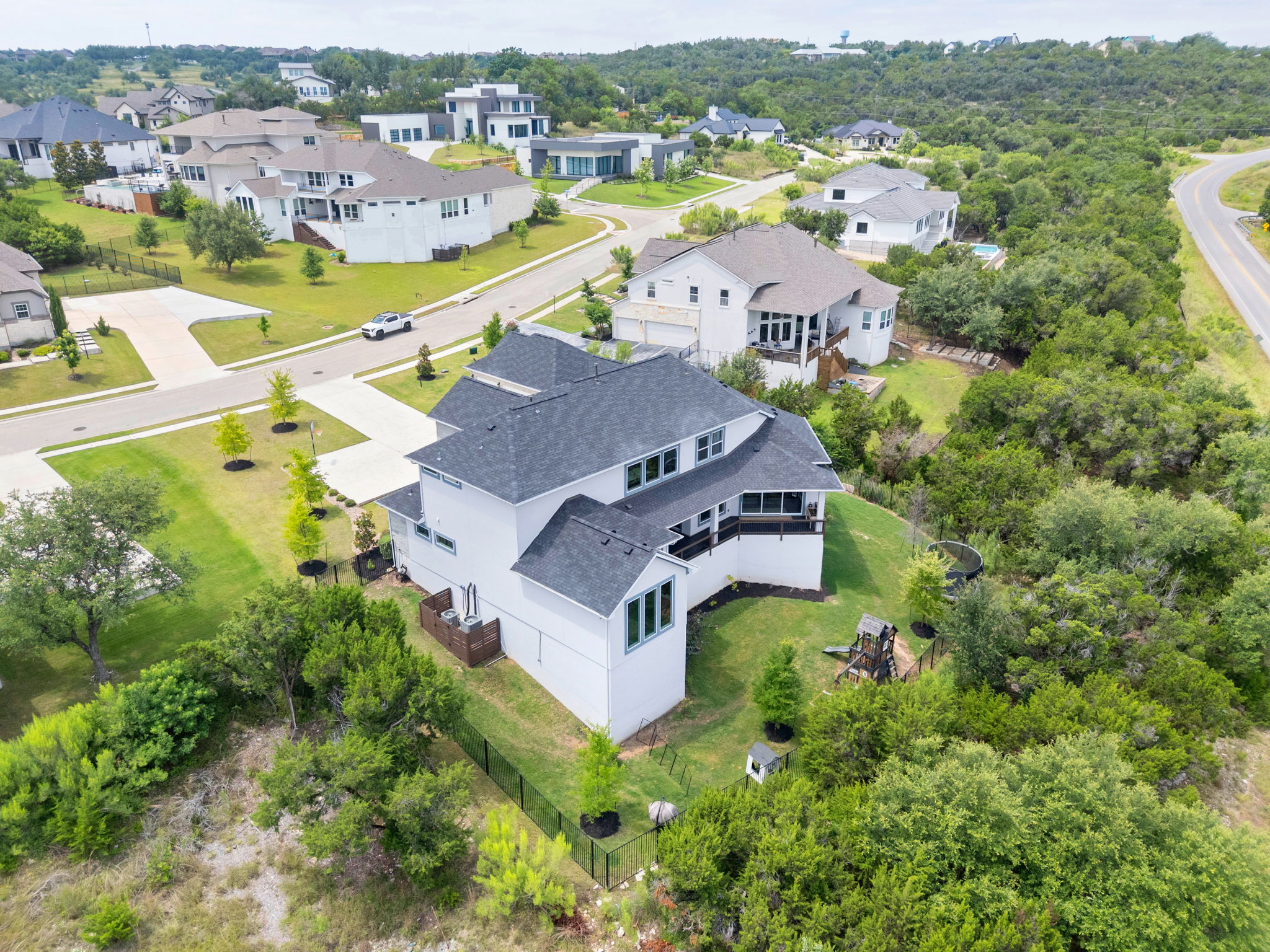 104 Lodestone Cove Austin, TX 78738 - Photo 36 of 40 An aerial perspective reveals a modern residence nestled amidst a vibrant green landscape and a tranquil neighborhood.