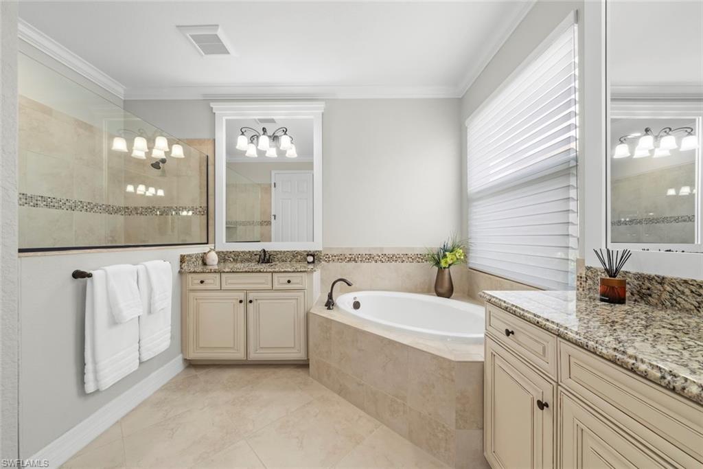 12692 Kinross Lane Naples, FL 34120 - Photo 21 of 47 Primary bathroom with tiled walk-in shower with a glass enclosure, separate soaking tub, and a dual vanity with granite countertops