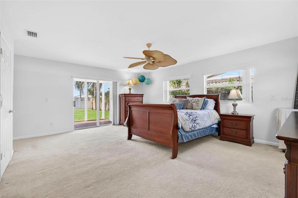 10100 Commodore Drive Seminole, FL 33776 - Photo 28 of 43 a bedroom with a large bed and a chandelier fan