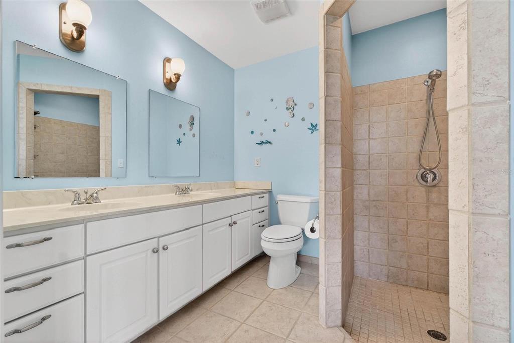 10100 Commodore Drive Seminole, FL 33776 - Photo 30 of 43 a bathroom with a double vanity sink toilet and shower