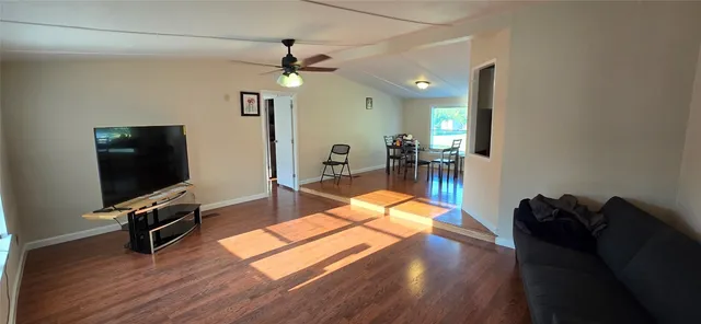 a living room with furniture a flat screen tv and wooden floor