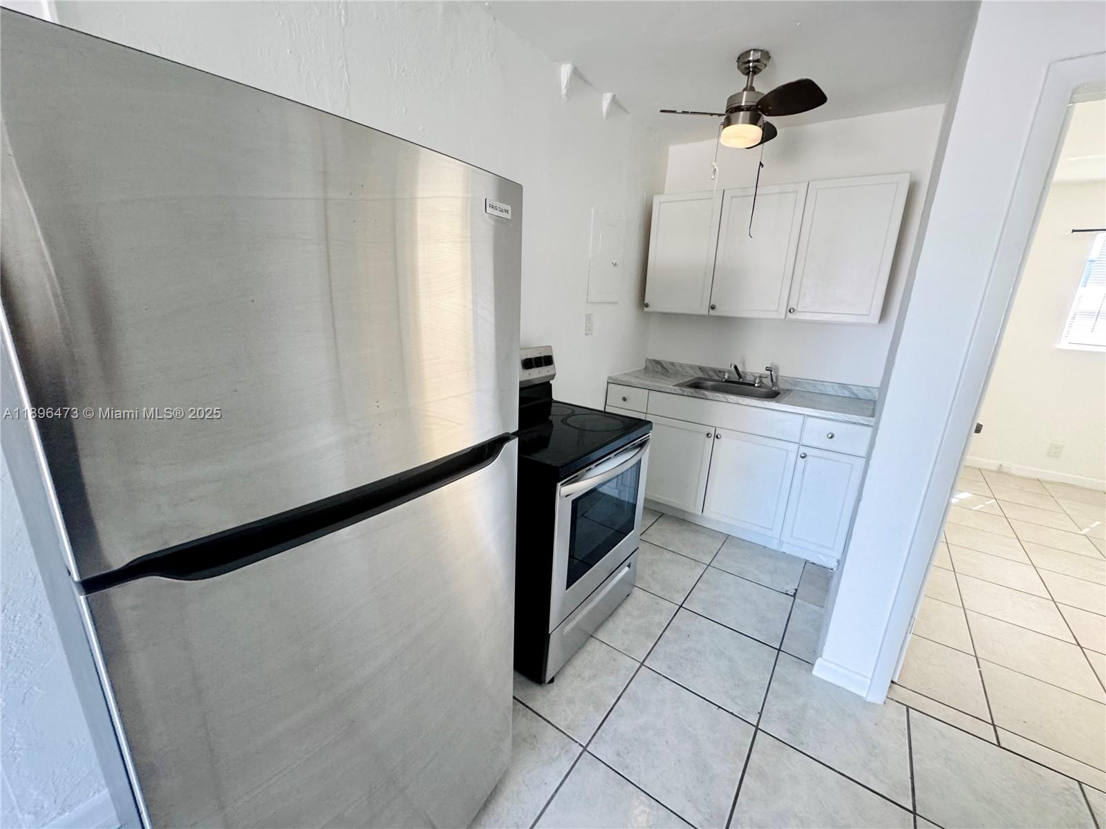 825 Northwest 9th Street, Unit 825 Hallandale Beach, FL 33009 - Photo 9 of 18 a kitchen with granite countertop a refrigerator a sink and white cabinets