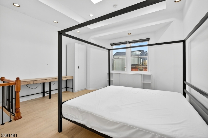 159 Palisade Avenue, Unit 2R Jersey City, NJ 07306 - Photo 14 of 26 a spacious bedroom with a bed and a dresser with mirror