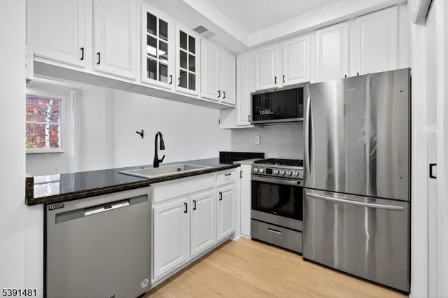 a kitchen with stainless steel appliances a sink stove refrigerator and cabinets