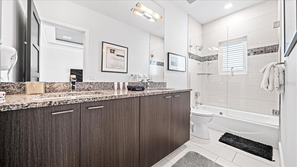 331 Muirfield Loop Reunion, FL 34747 - Photo 19 of 100 a bathroom with a granite countertop sink toilet and shower