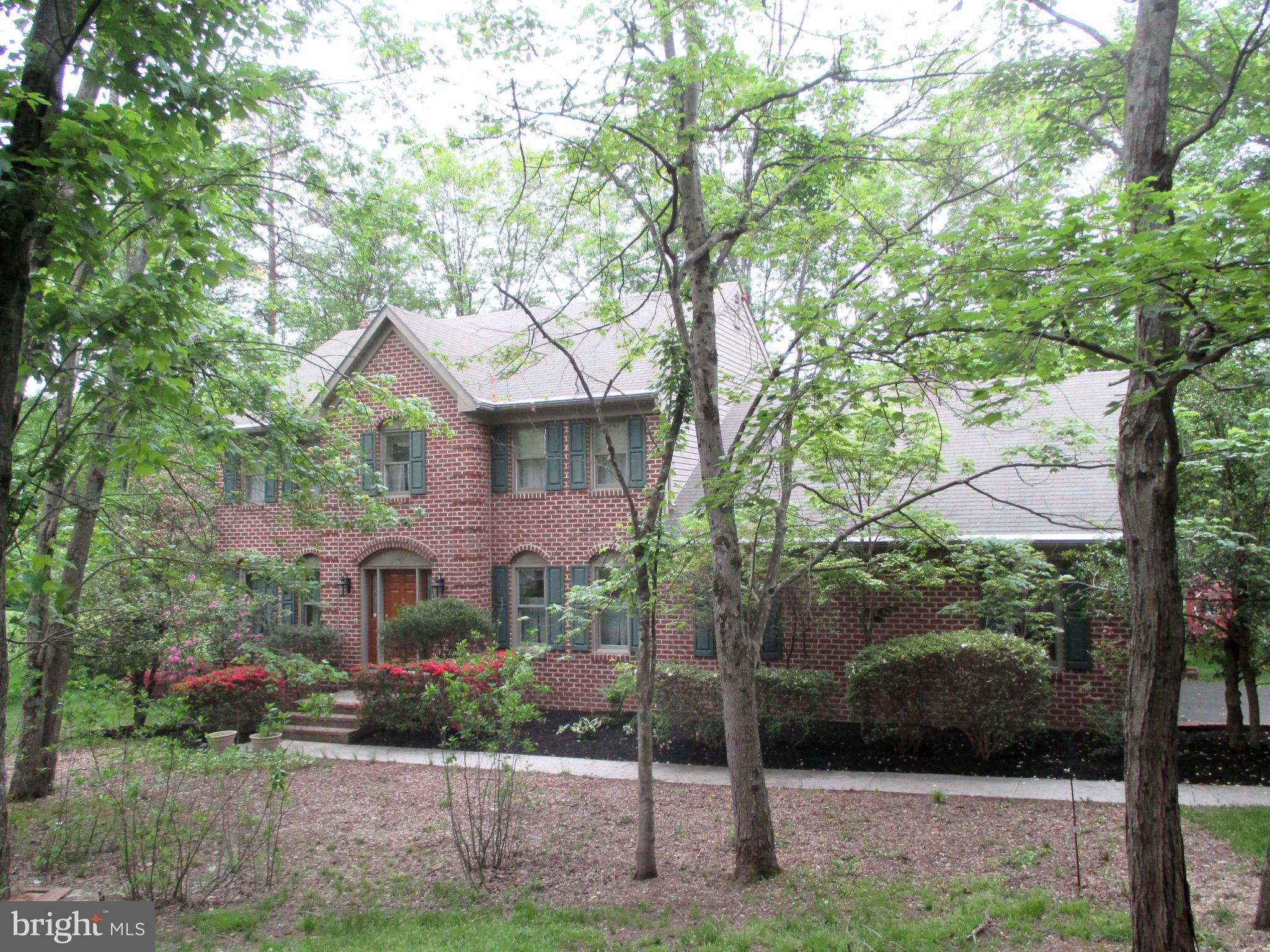 a front view of a house with a yard and large tree