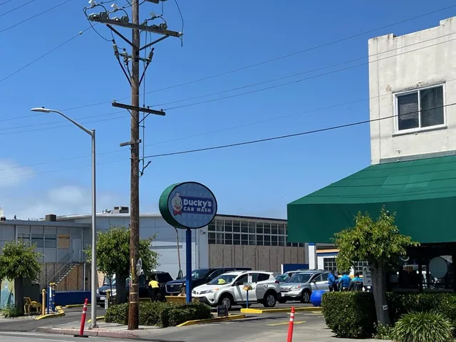 a front view of a building with garden and parking