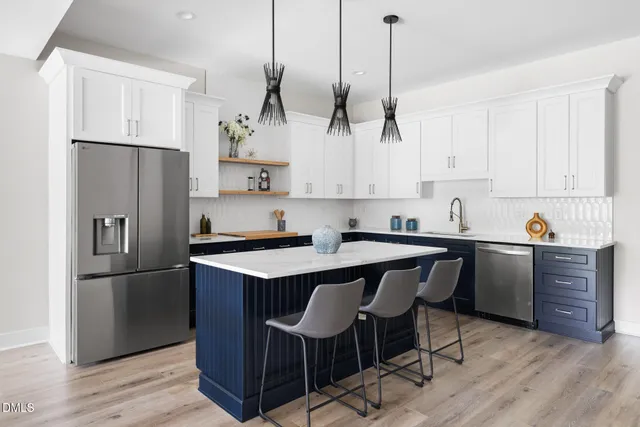 a kitchen with stainless steel appliances granite countertop wooden floors sink stove and white cabinets