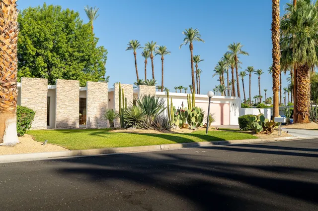 a view of a house with a yard and palm trees