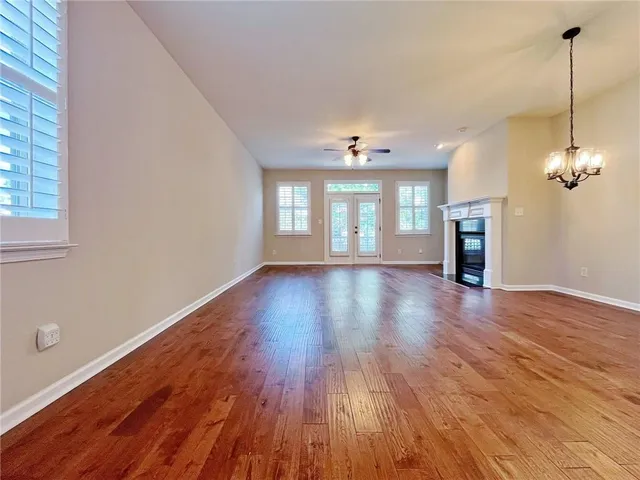 a view of an empty room with wooden floor and a fireplace