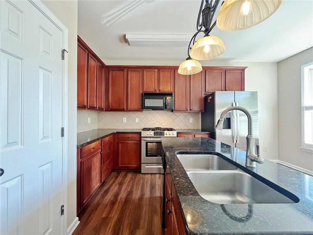 525 Grove Field Court Northwest Suwanee, GA 30024 - Photo 27 of 57 a kitchen with kitchen island granite countertop a sink a counter space appliances and cabinets