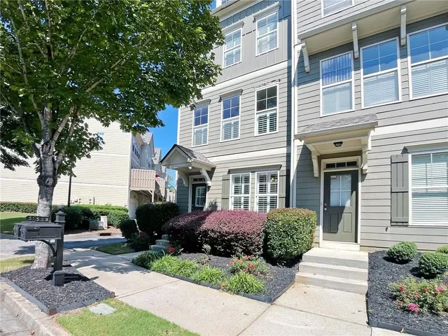 a front view of a house with garden and trees