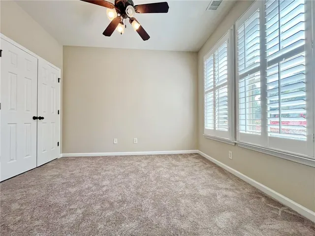an empty room with windows and chandelier fan