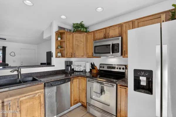 a kitchen with granite countertop a stove a sink and a refrigerator