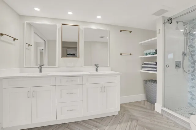 a bathroom with a double vanity sink a toilet and a shower