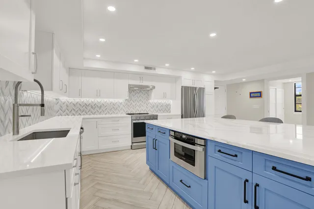 a large kitchen with stainless steel appliances granite countertop a lot of counter space and wooden floor