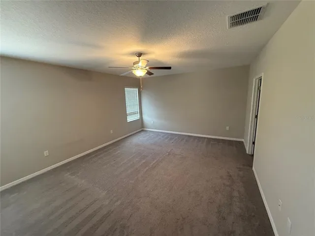 an empty room with a chandelier fan and windows