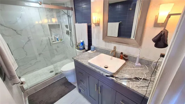 a bathroom with a granite countertop sink toilet and shower