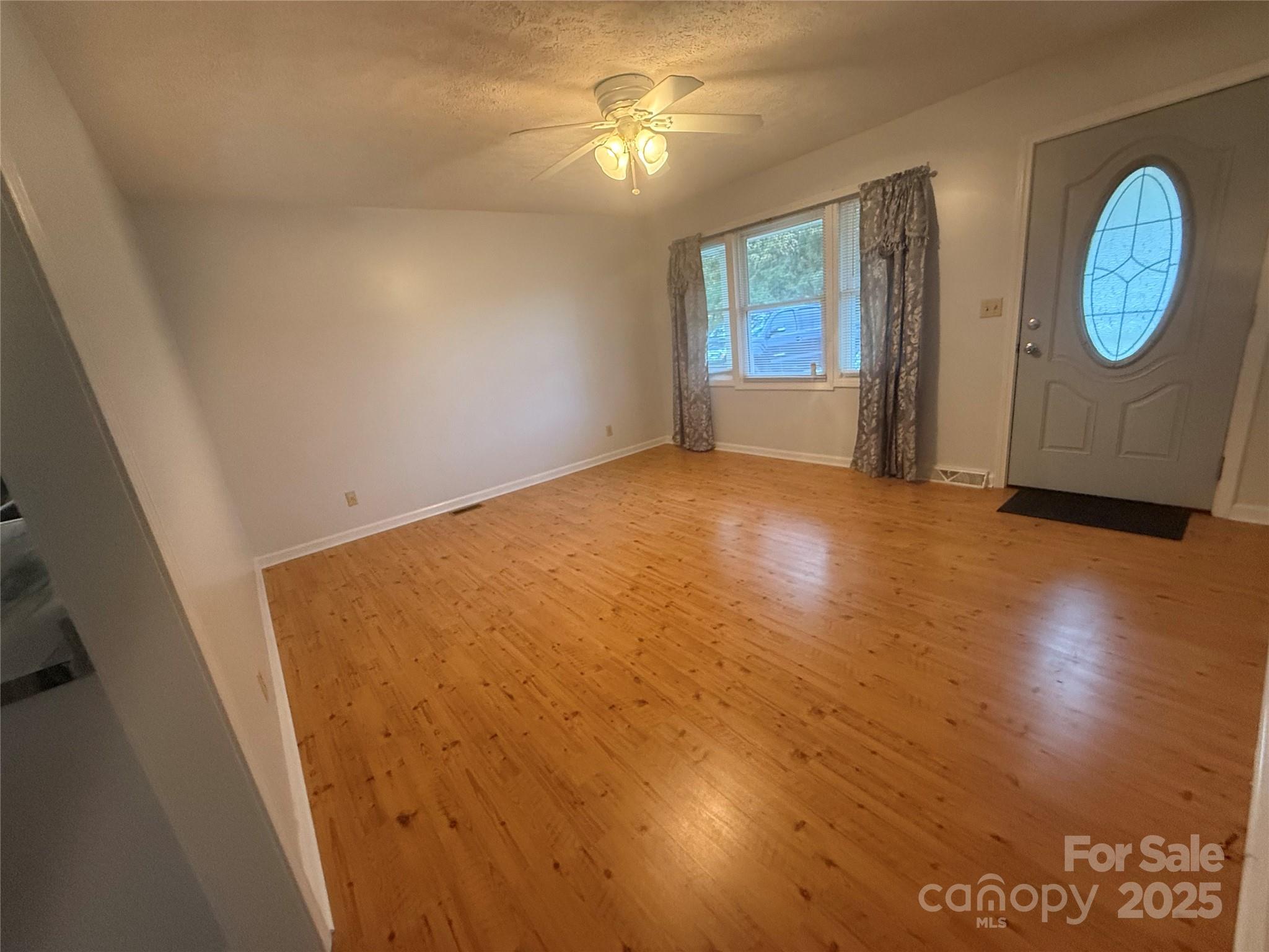 5601 Howard Gap Road Flat Rock, NC 28731 - Photo 7 of 21 a view of empty room with wooden floor and fan