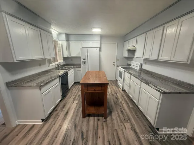 a kitchen with stainless steel appliances a stove a sink dishwasher a refrigerator and cabinets with wooden floor