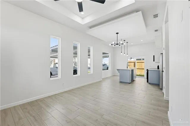 a view of a big room with chandelier fan and windows