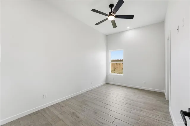 an empty room with wooden floor and a ceiling fan