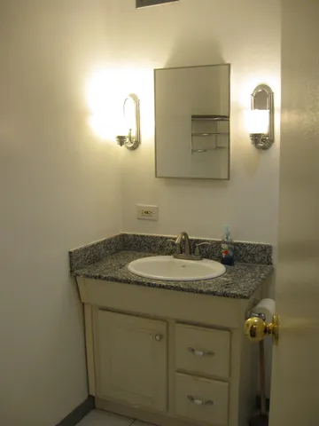 a bathroom with a granite countertop toilet a sink and mirror